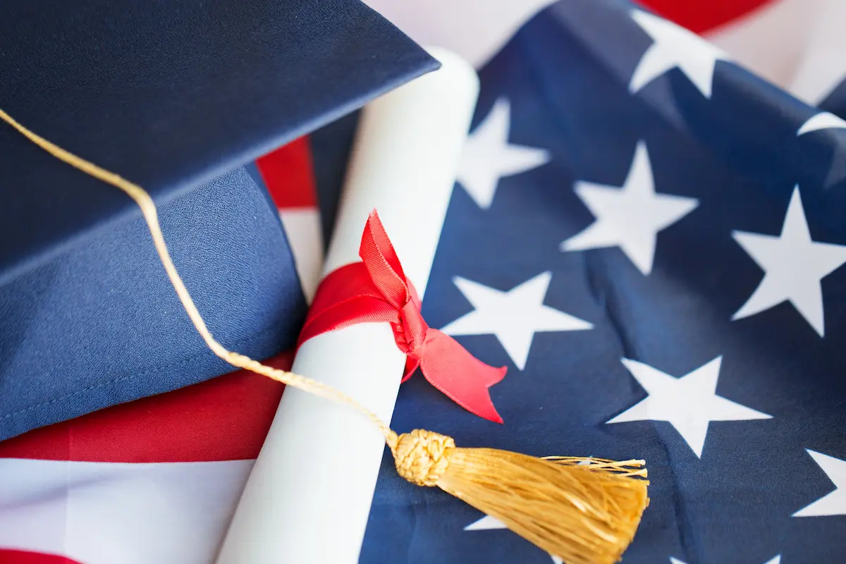 Graduation cap and diploma on top of the American flag.